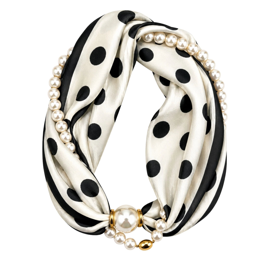 A black and white polka dot silk scarf styled as an infinity loop, decorated with strands of white faux pearls and a gold-toned clasp featuring a large pearl.