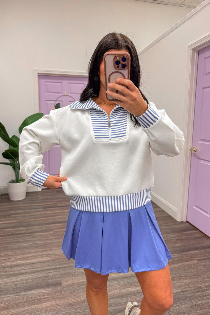 Showing the fit of white and blue 1/4 zip athleisure top
