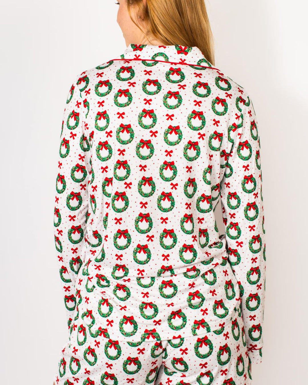 Person showing back of festive pajama top with Christmas wreath pattern