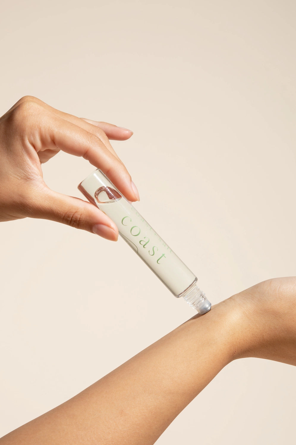 Someone showing application of Coast + Salt  Coast Roll-on perfume bottle 