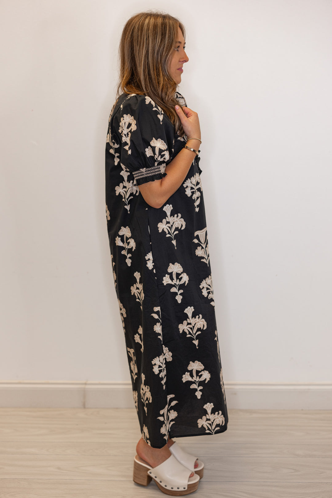 side view of Women's black midi dress with taupe botanical floral print and ruffle detail