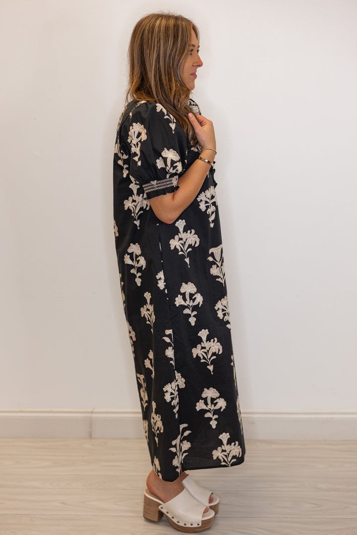 side view of Women's black midi dress with taupe botanical floral print and ruffle detail