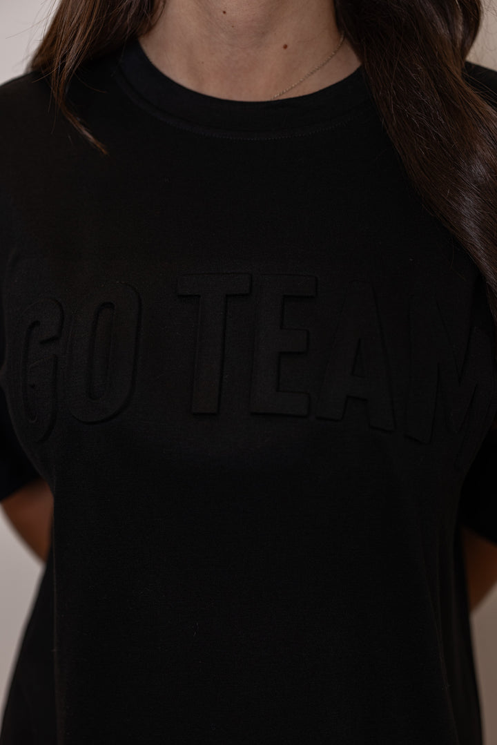 Women's black lightweight top with embossed 'Go Team' in center by Jess Lea, showing up close view of embossed lettering