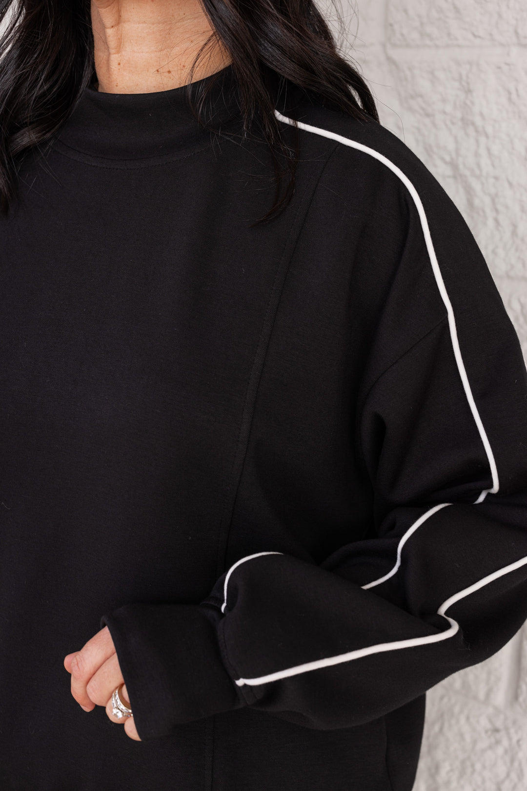 Women's black scuba knit mock neck top by Rae Mode showing ivory piping on the sleeves