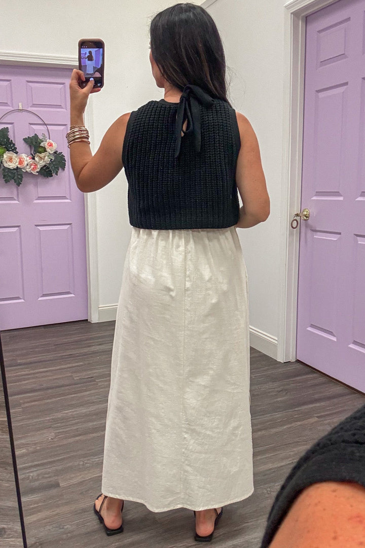 midi dress with black sleeveless bow tie back sweater top and cream skirt