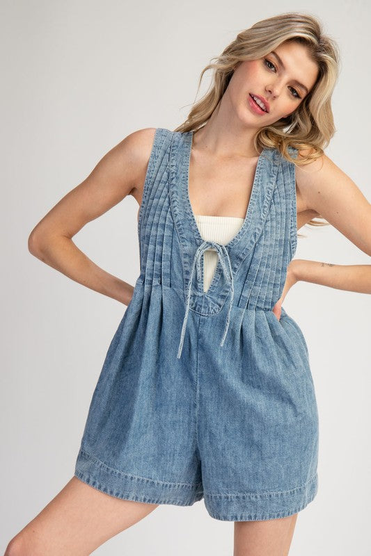 Washed blue denim sleeveless romper with a ruched bodice and bow tie v neck