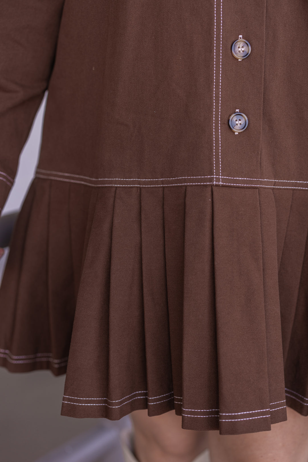 Women's brown denim twill button front dress with cream stitching trim by Entro showing pleated bottom hem