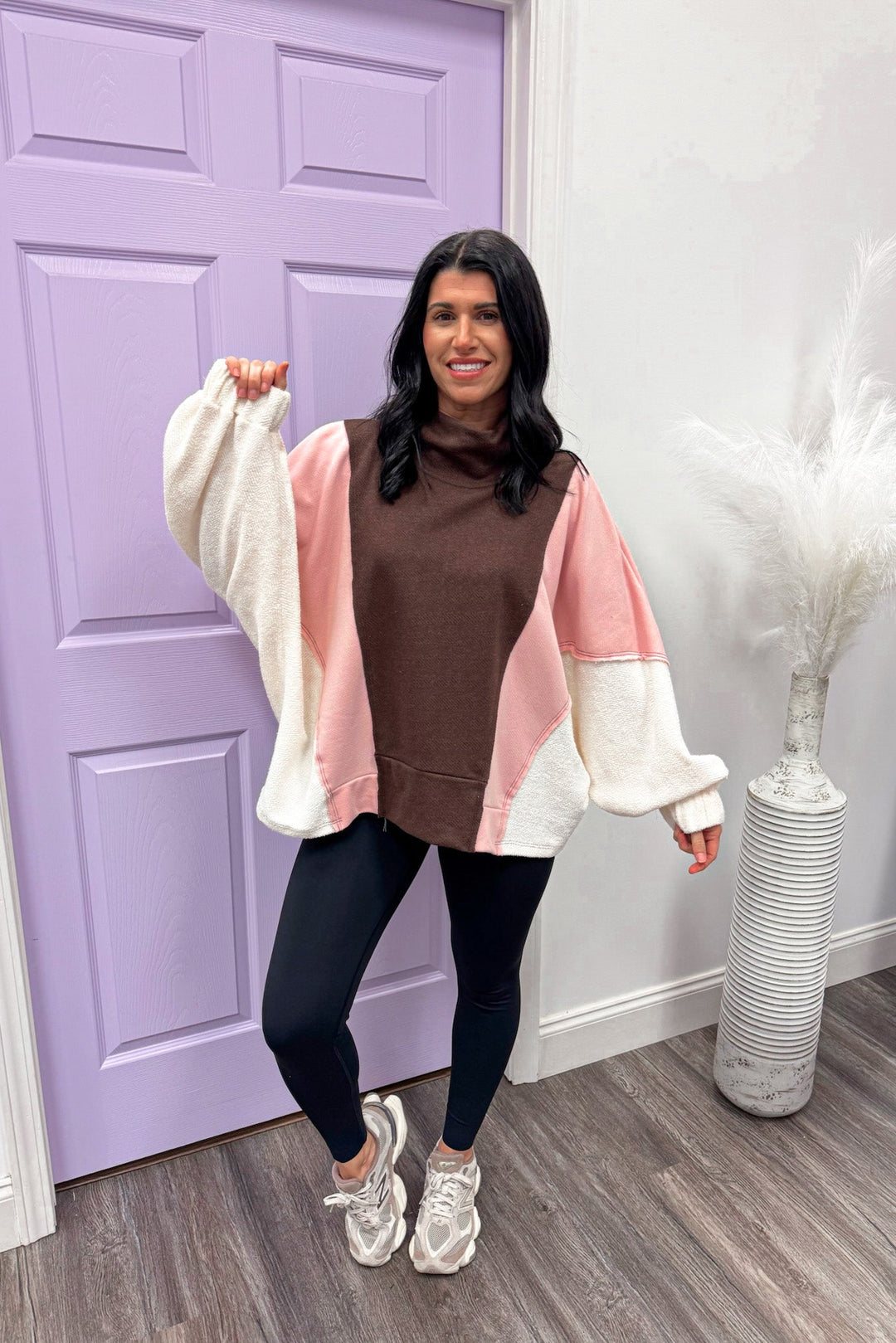 Woman wearing a colorful sweater in front of a purple door.