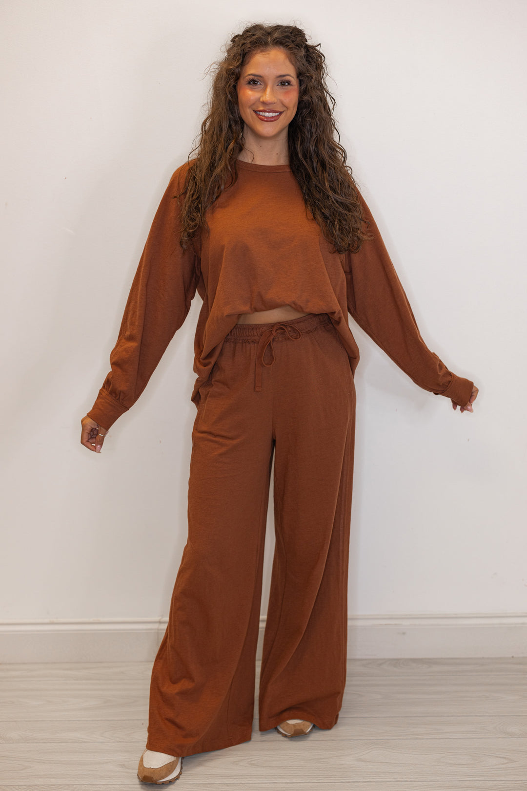 Women's chestnut brown athleisure long sleeve tee and pants set shown with a front tuck and sneakers