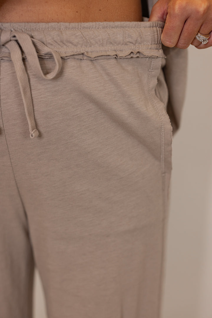 Close-up of women's beige lounge cotton pants with a drawstring waistband.