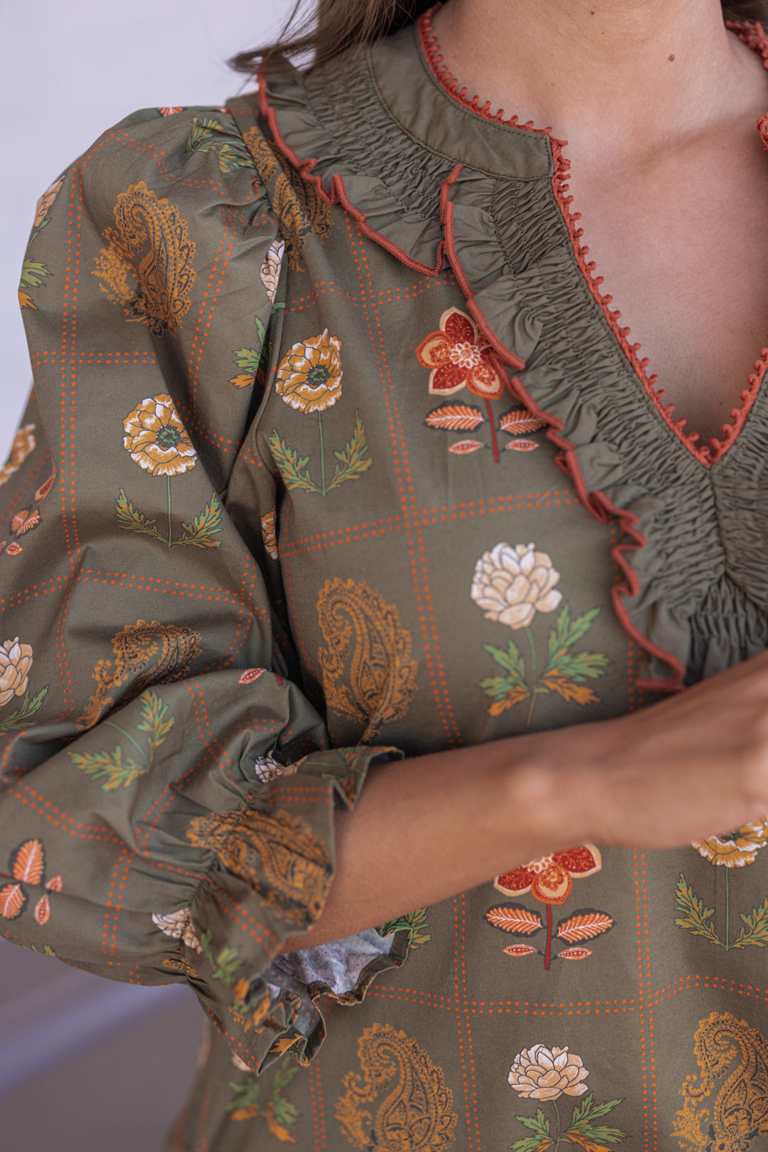 Women's olive dress with floral border print in orange and peach by Entro showing ruffled ruched v neckline