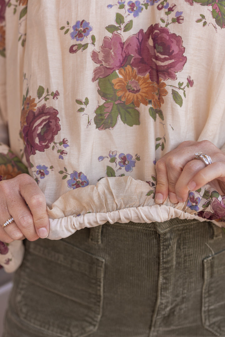 Women's ecru bubble hem top with large burgundy and olive floral print by Entro showing bubble bottom hem