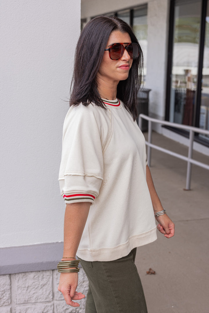 Women's ecru french terry knit top with olive and red striped trim by Entro showing side view