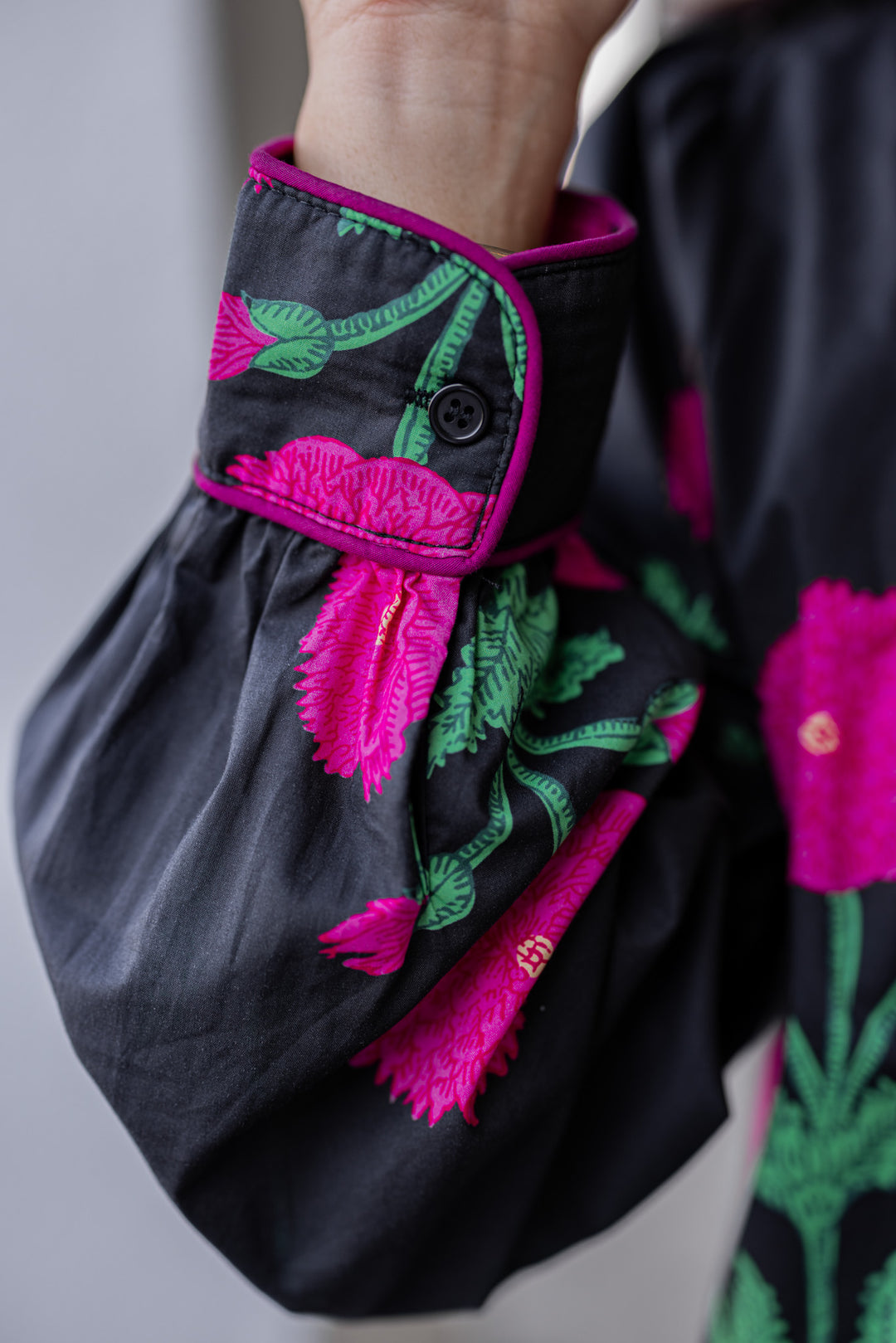 Women's black midi dress with hot pink floral print and hot pink piping trim by Jodifl showing up close of sleeve detail