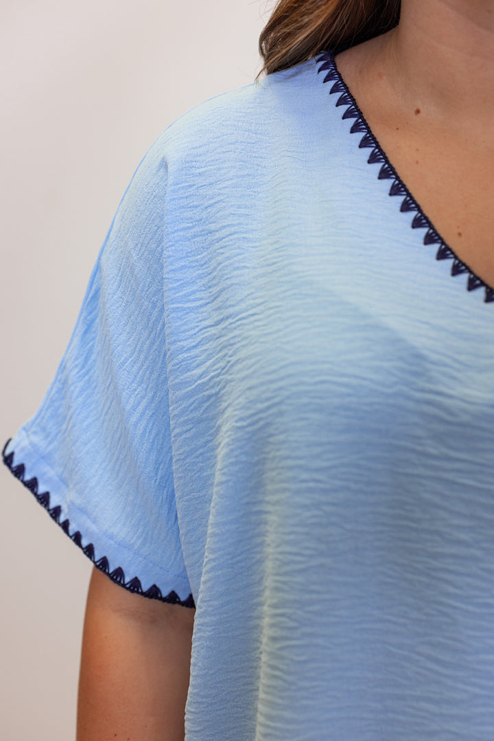 Sky blue lightweight crinkle top by Jodifl showing up close view of embroidery stitched trim