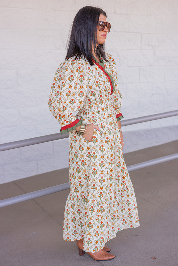 Women's ecru midi dress with orange and green floral print and ruffle trim by Entro showing full side view