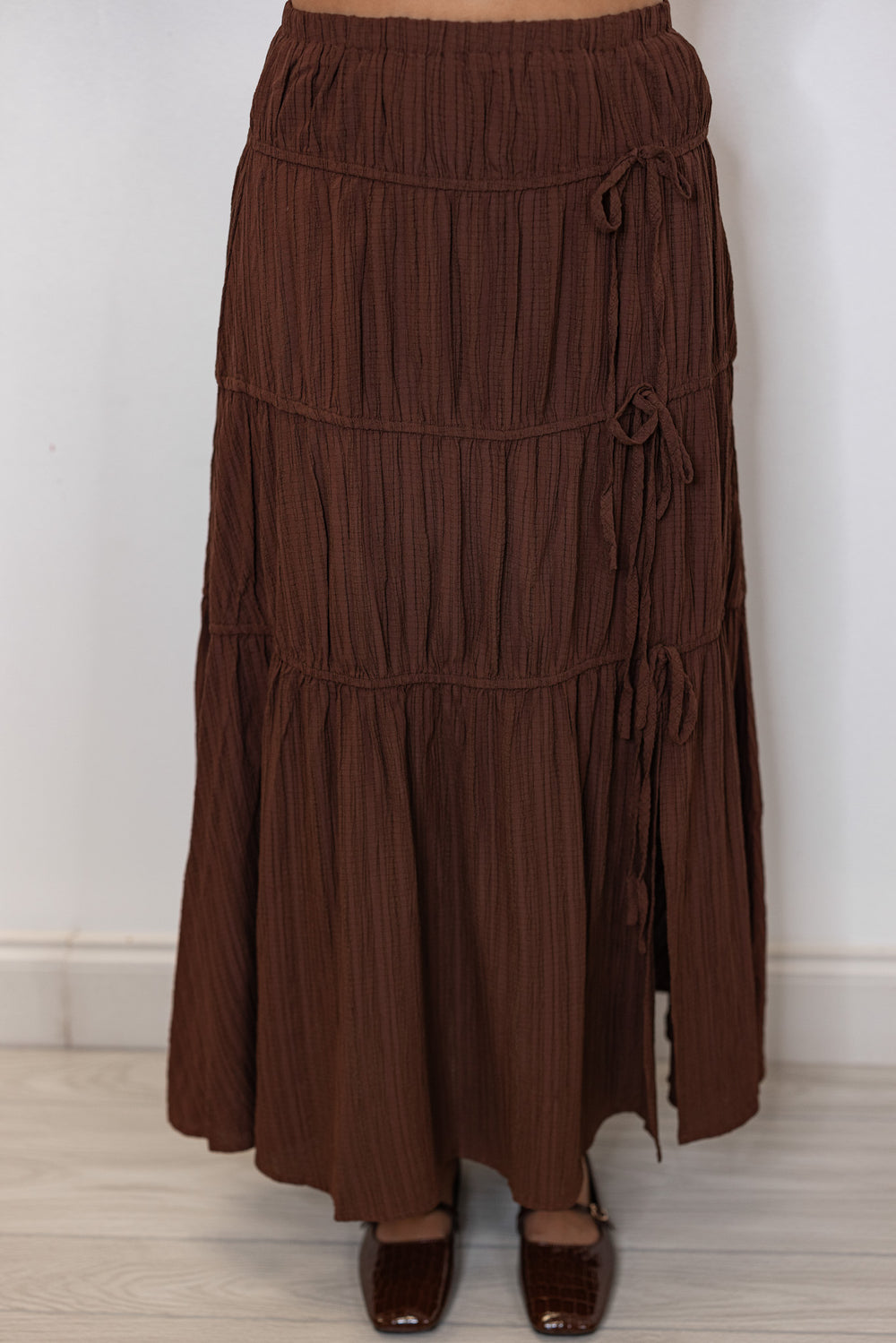 Women's pleated chocolate brown tiered midi skirt with bow ties down one side by In February showing up close front view
