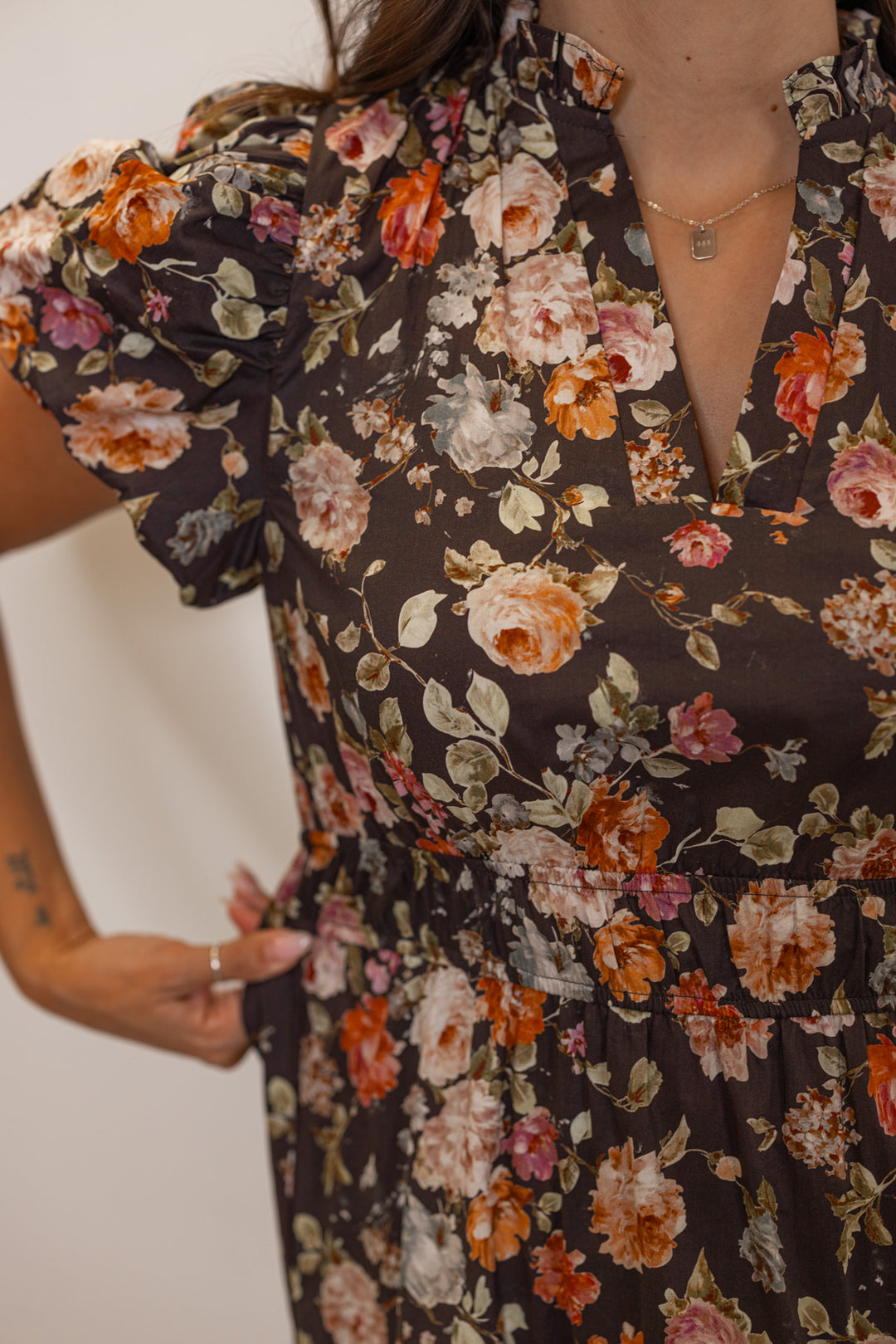 Women's chocolate brown midi dress with empire waist and multicolor floral print by Entro showing elastic waistband stretch