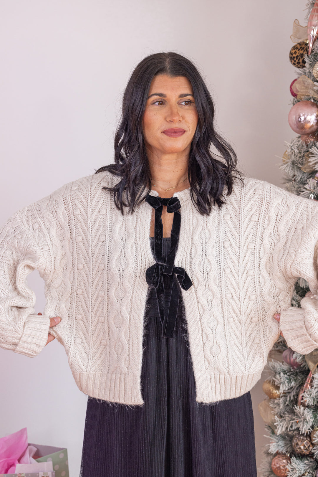 Women's oatmeal cable knit sweater cardigan with black bow tie closure by Blu pepper showing loose relaxed fit