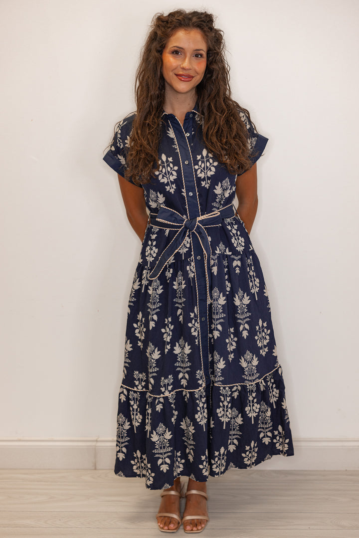 Woman wearing a navy blue floral dress against a white background