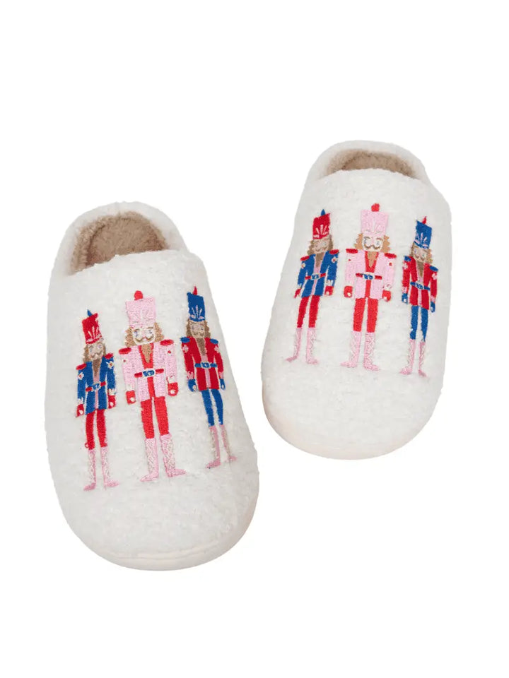 Pair of white slippers with nutcracker design on a white background