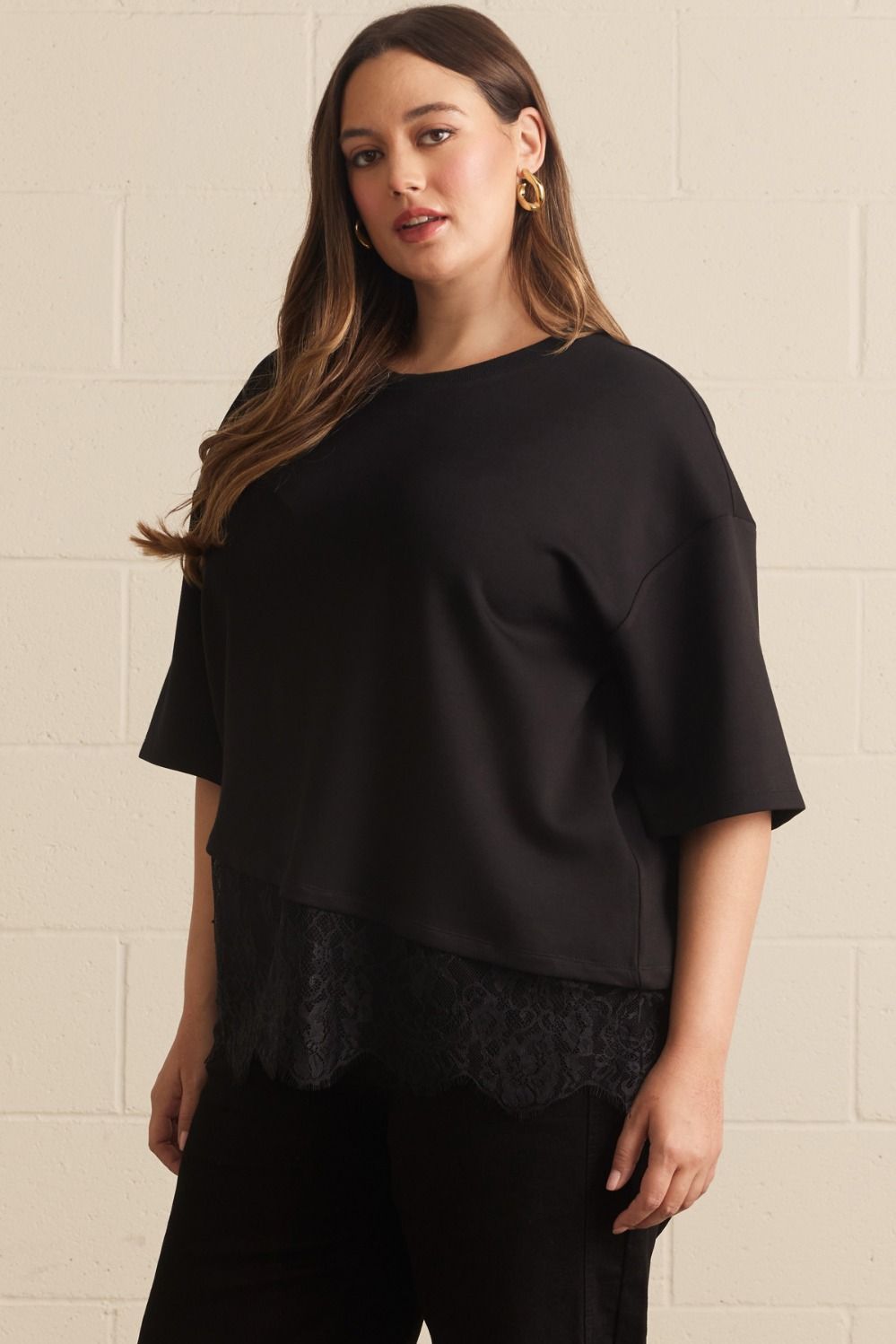Entro plus size black top with a crew neckline and an asymmetrical tiered lace detail at the hem