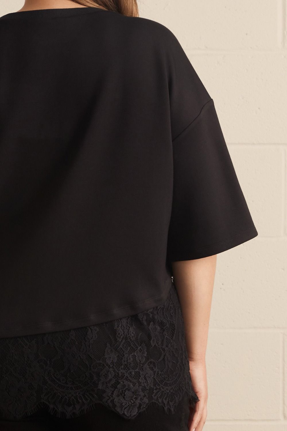 Entro plus size black top with asymmetrical tiered lace detail at the hem and a relaxed silhouette