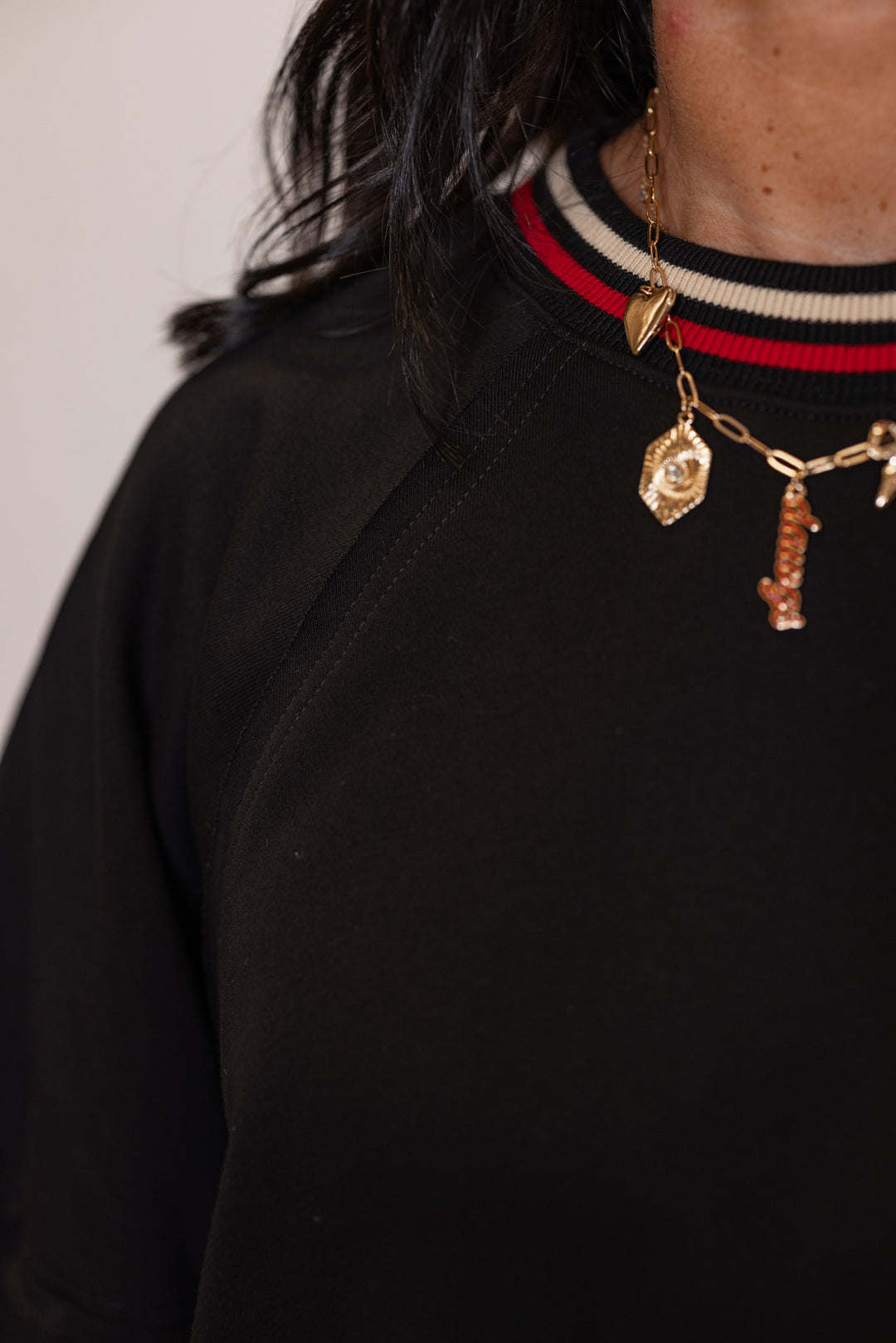 Women's black french terry knit top with cream and red striped trim by Entro showing striped trim details