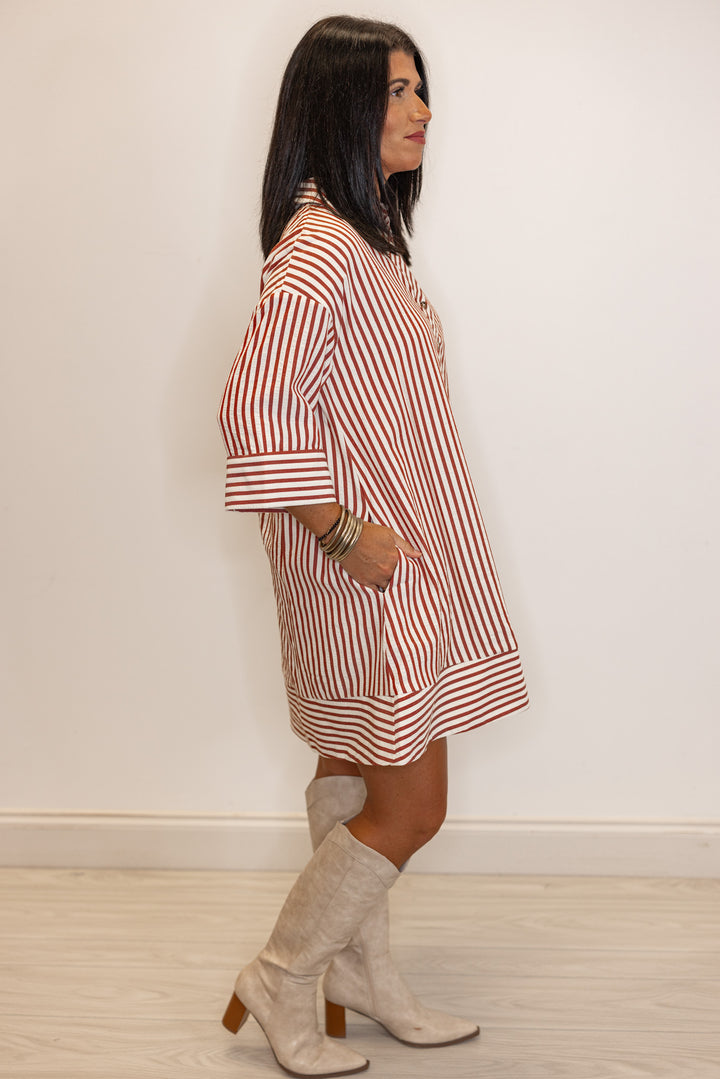 Side view of Woman's rust and ivory striped dress with pockets 