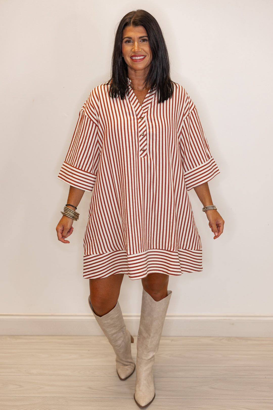 Woman's rust and ivory striped dress with beige knee-high boots 