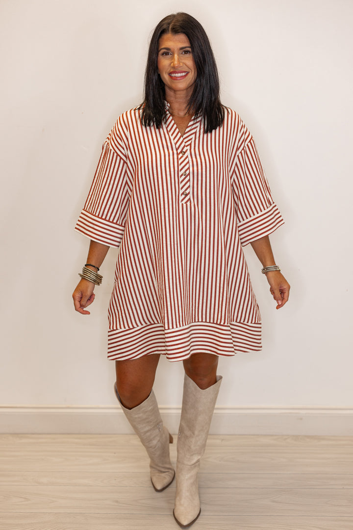 Woman's rust and ivory striped dress with beige knee-high boots 