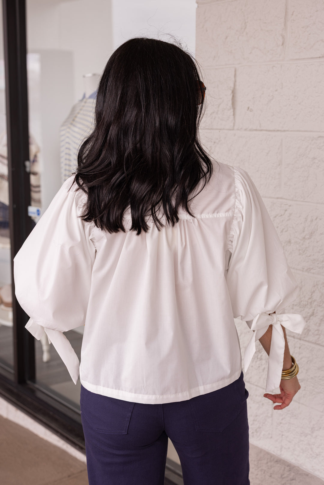 Back view of white blouse paired with navy pants