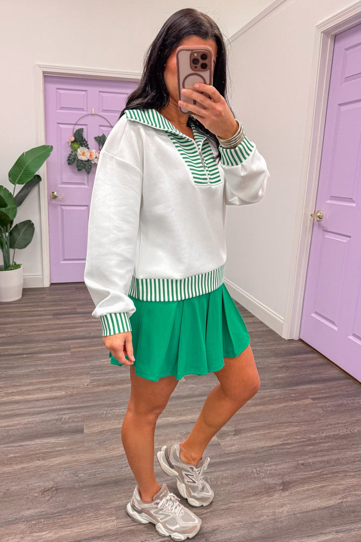 Side view of white pullover paired with green skort