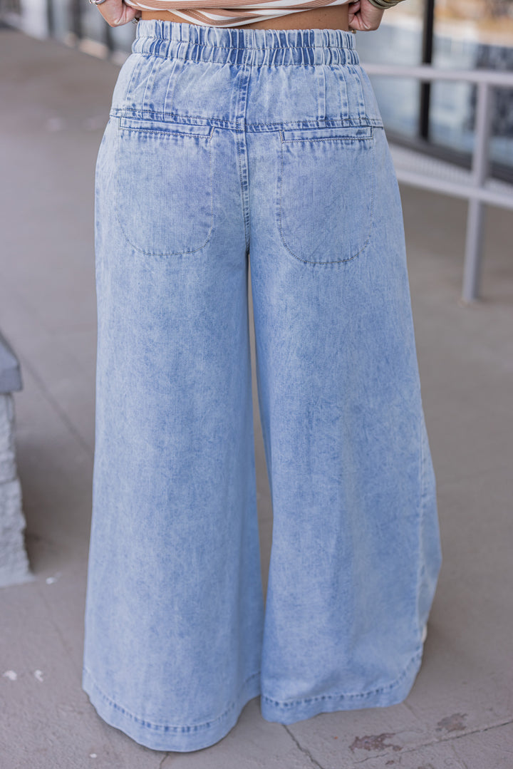 Palazzo style wide leg light blue washed denim pants with button fly by ee:some showing up close back view
