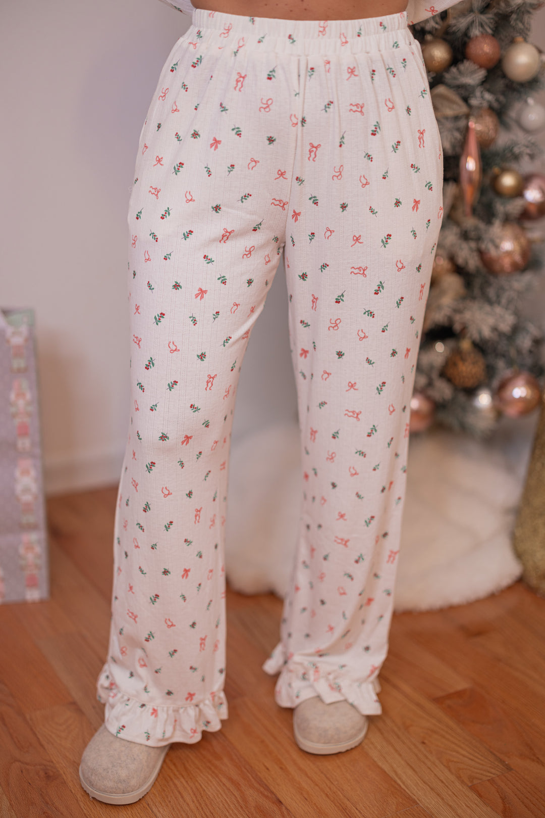 Women's cream pointelle knit pajamas with red, pink and green holly and bow tie print by Peach Love California showing pant's front view
