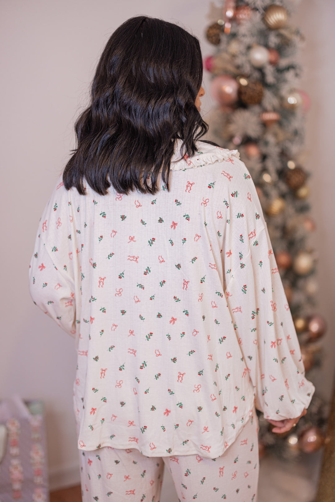 Women's cream pointelle knit pajamas with red, pink and green holly and bow tie print by Peach Love California showing top's back view