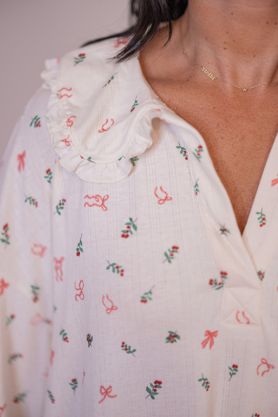 Women's cream pointelle knit pajamas with red, pink and green holly and bow tie print by Peach Love California showing ruffled collar