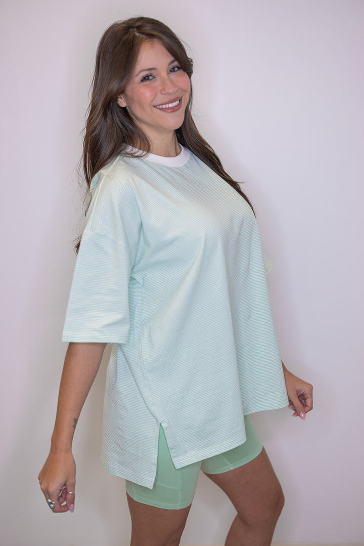 Women's mint green and white striped knit oversized top by Wishlist showing side slits in bottom hem