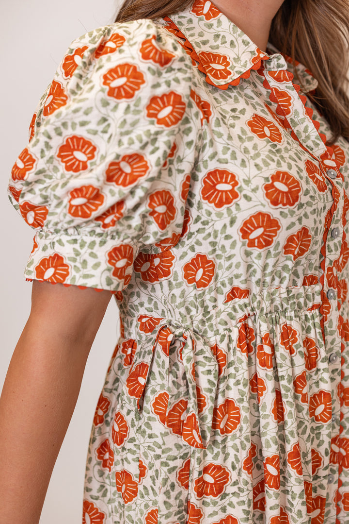 Women's cream button front midi dress with rust floral print by Entro showing side adjustable cinch ties