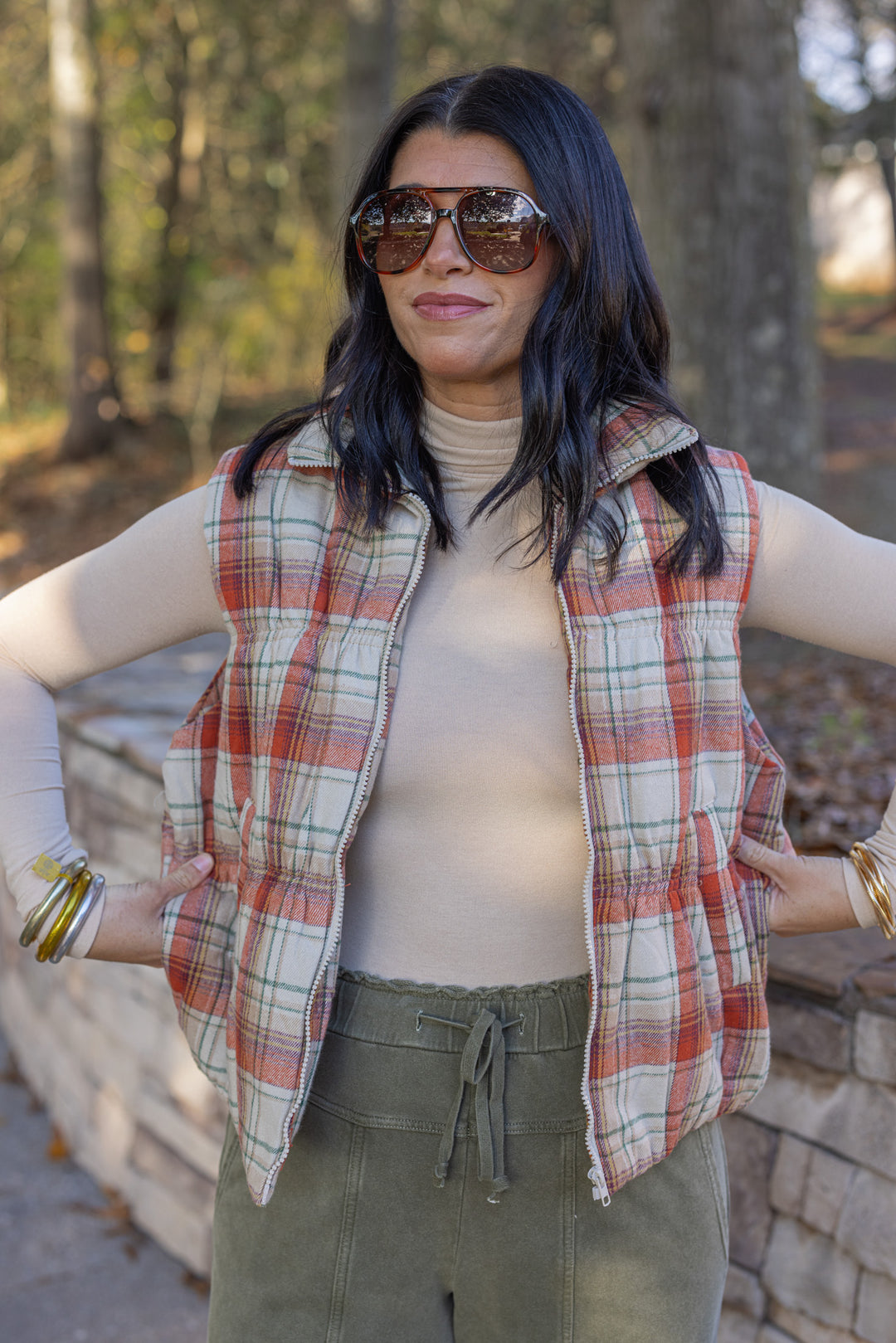 Women's quilted puffer vest in taupe, brown, persimmon orange and green plaid by Easel showing true to size fit
